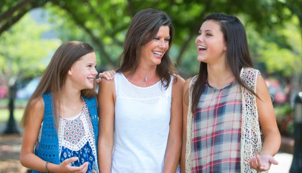 Mother laughing outdoors with her two daughters, all with confident smiles at Delta Smiles in Antioch and Brentwood, CA